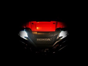 Teaser image of front end of red Honda Pioneer all-terrain vehicle against black background