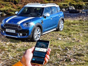 qMINI Countryman with hand holding phone showing MINI Connected app