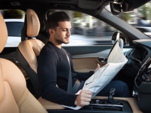 Autonomous Volvo with man reading newspaper