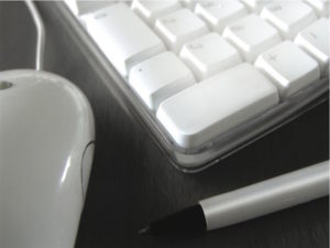 Cropped image of Mac keyboard and mouse and a pen
