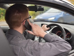 Man driving car using hand-held mobile phone