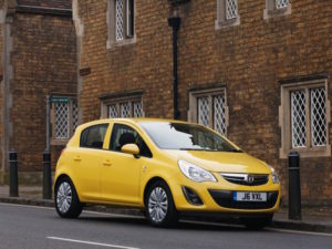 Yellow Vauxhall Corsa D on street outside building