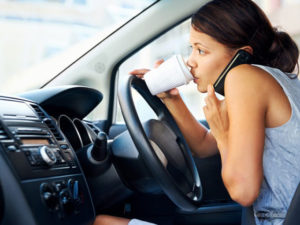 Businesswoman multitasking while driving, drinking coffee and talking on the phone-distractions