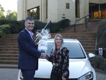 Nexus client development director Mike Palmer, presenting Acorn Stairlift's Jolene Shaw with a bottle of champagne to mark the milestone booking